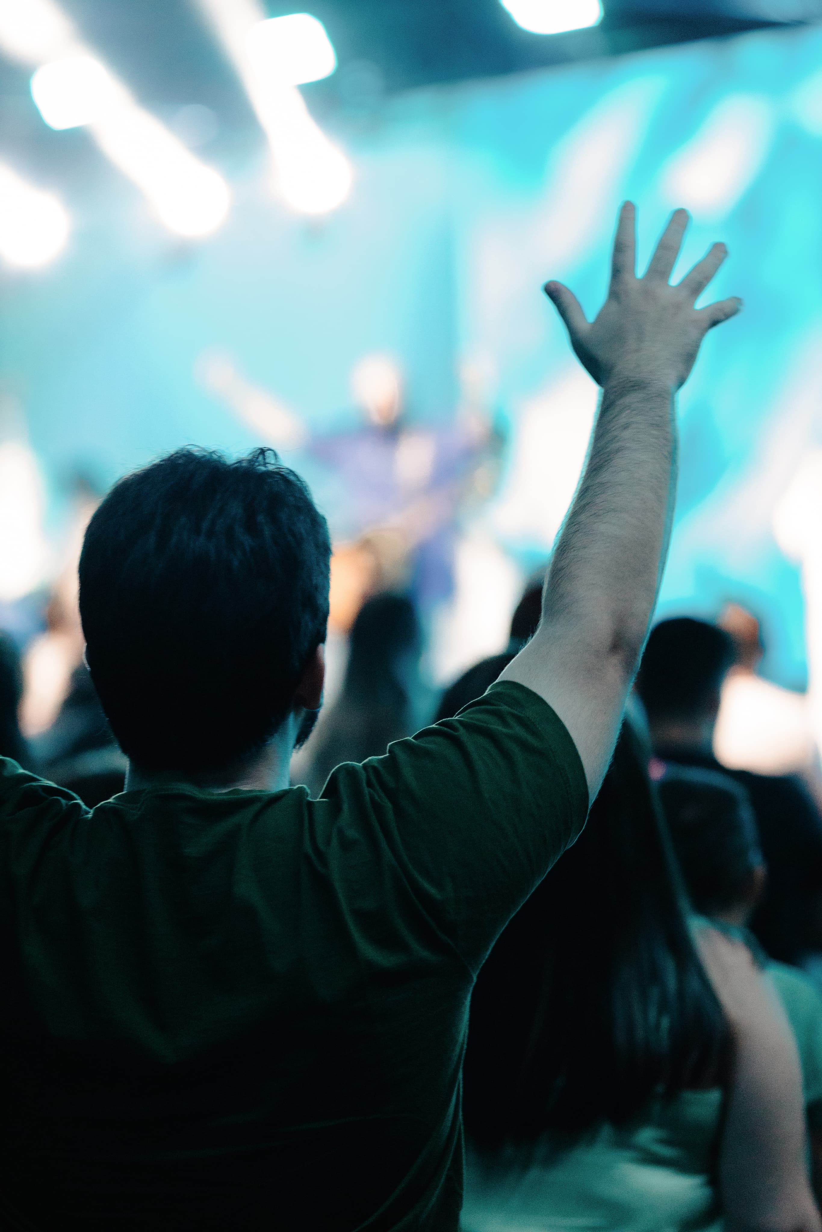 Pessoa com mão levantada em culto